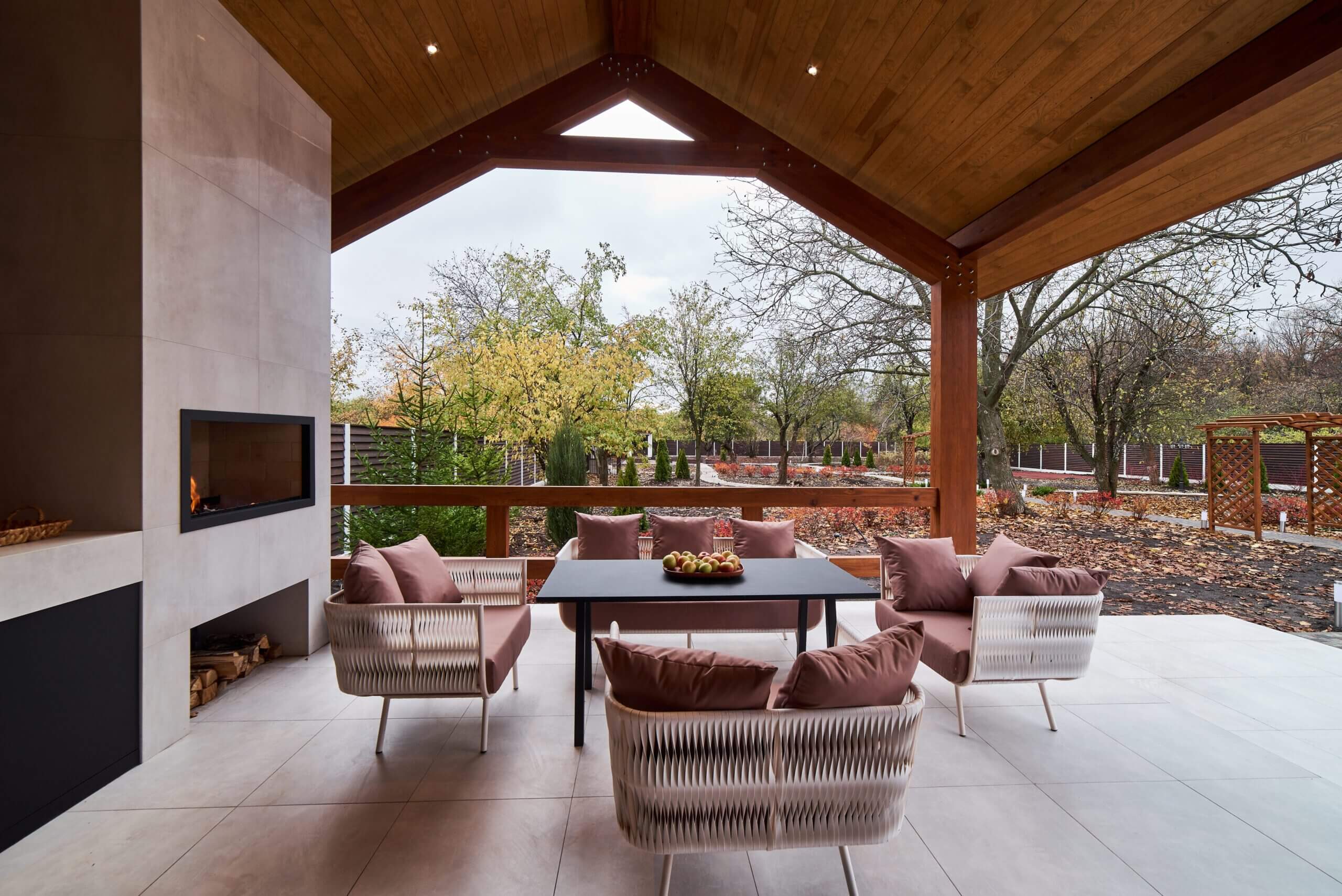 Stylish outdoor living space with comfortable seating and a modern fireplace, surrounded by lush greenery.