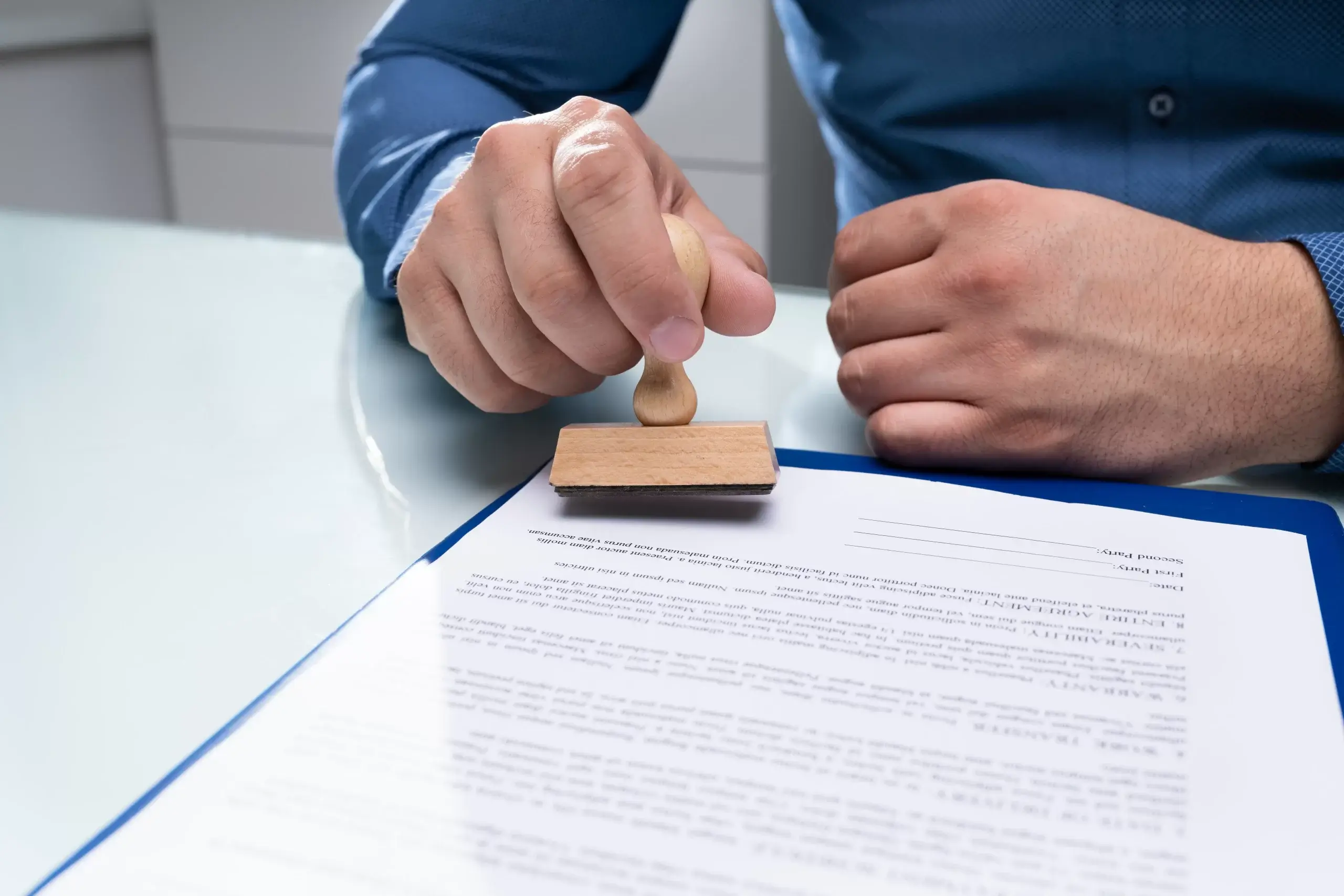 Close-up of a hand stamping a document with a wooden stamp.