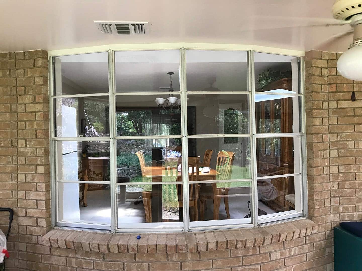 Before renovation: Dining area viewed through old multi-pane windows in a brick home in San Antonio.
