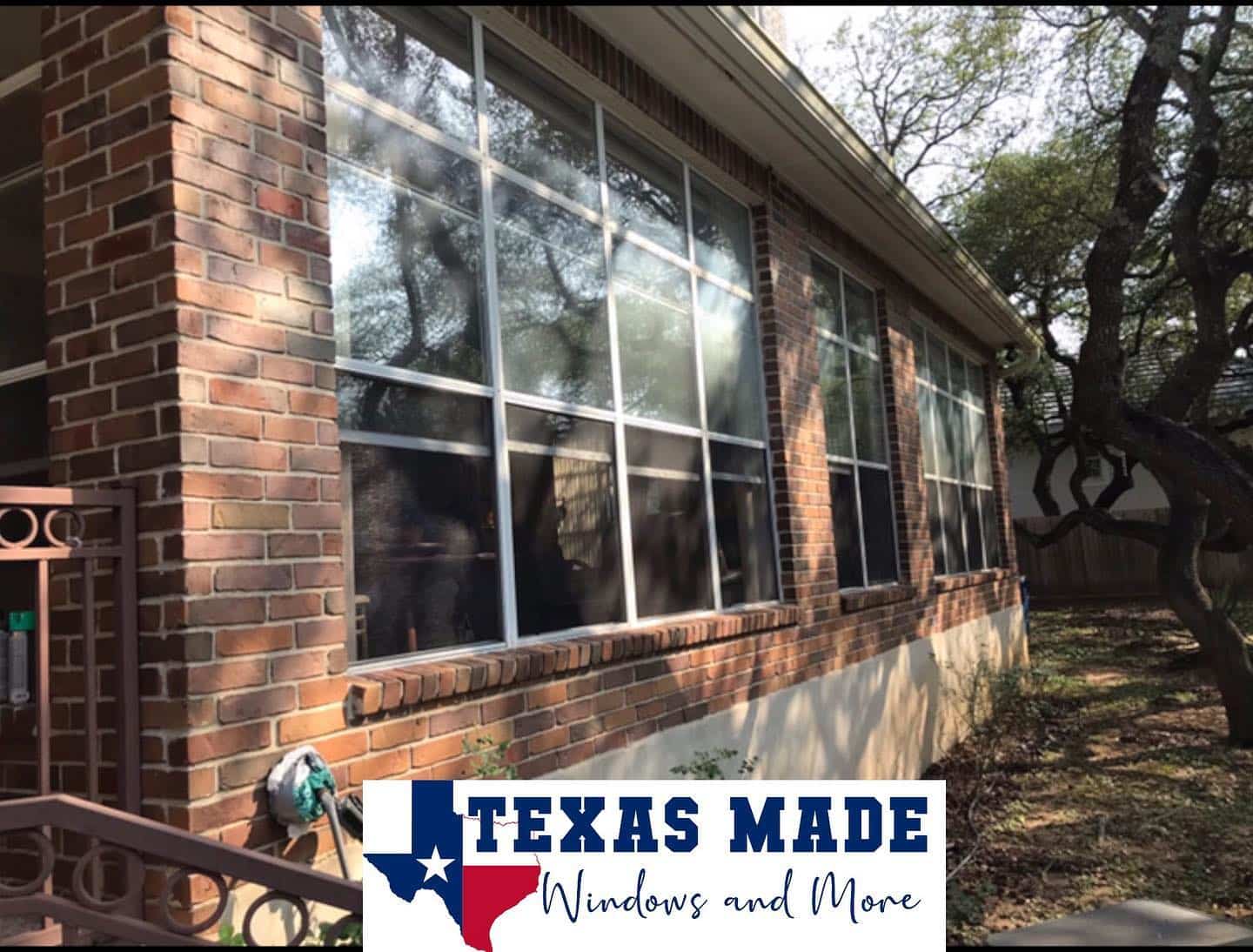 Large brick home with old, reflective windows before replacement in San Antonio.