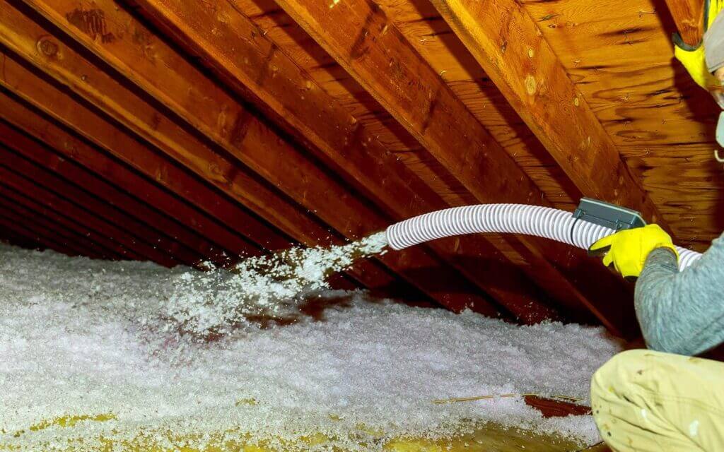 Professional applying loose-fill insulation in attic, San Antonio