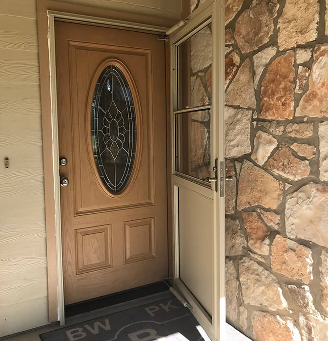 Elegant newly installed wooden door with decorative glass in a stone facade home in San Antonio.