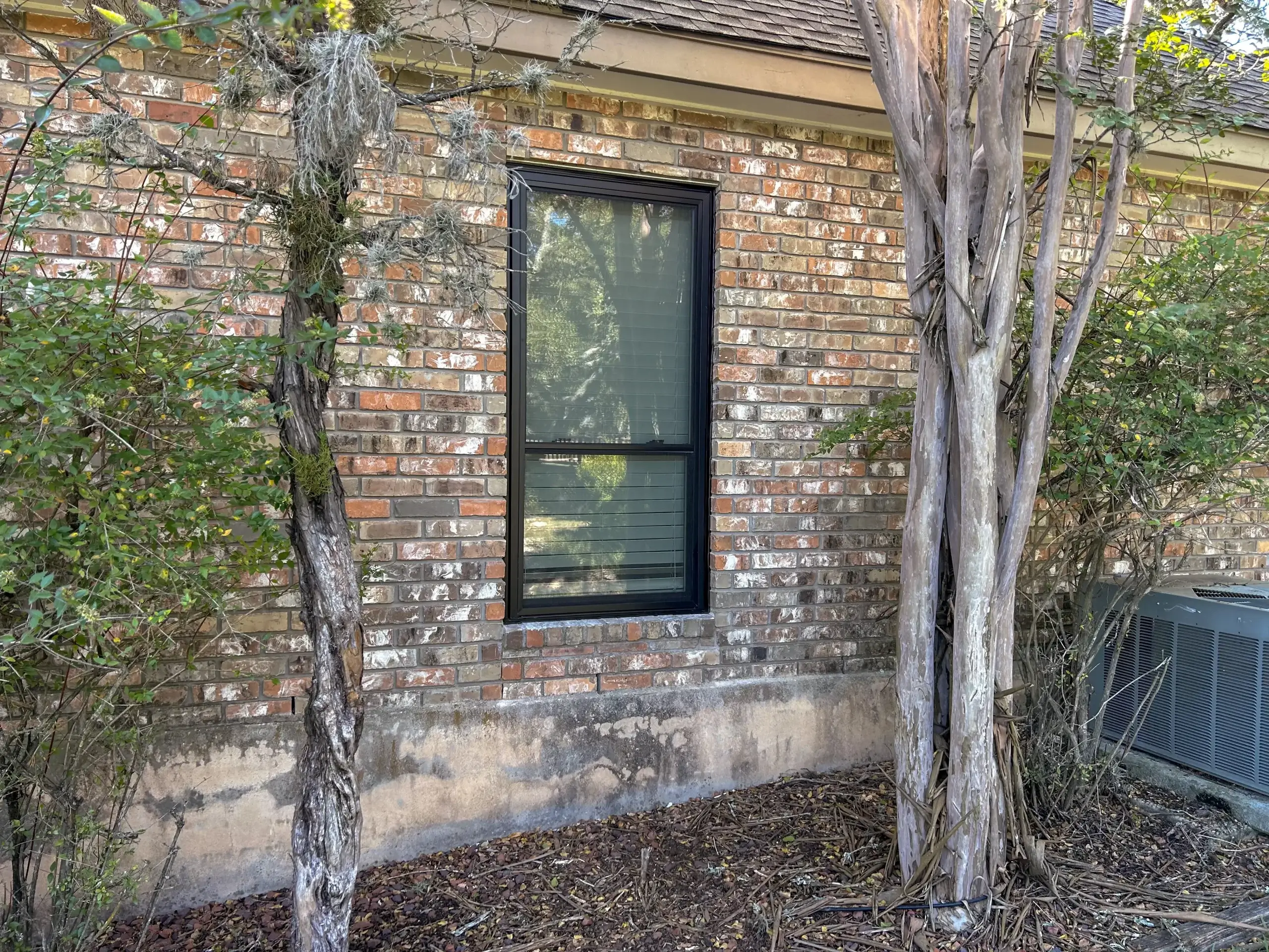After renovation: New black window installed on a brick house, enhancing both style and energy efficiency in San Antonio.