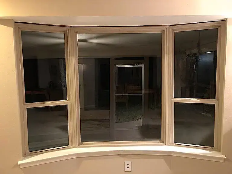 Spacious bow window installation with reflective glass in a San Antonio home interior.