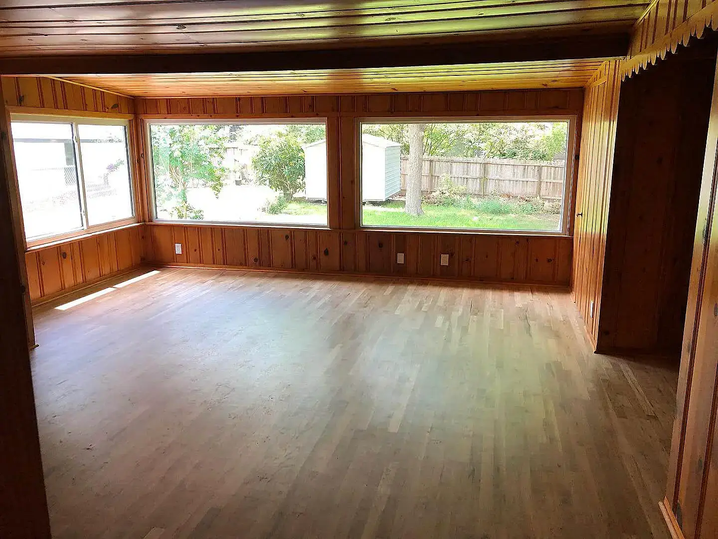 Large windows installed in a sunroom with wooden walls and light flooring in Corpus Christi.