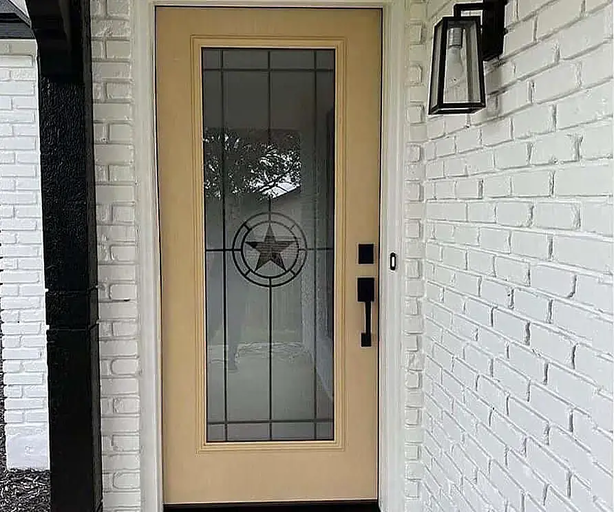 Elegant modern door with a Texas star design on glass, set in a white brick home in San Antonio