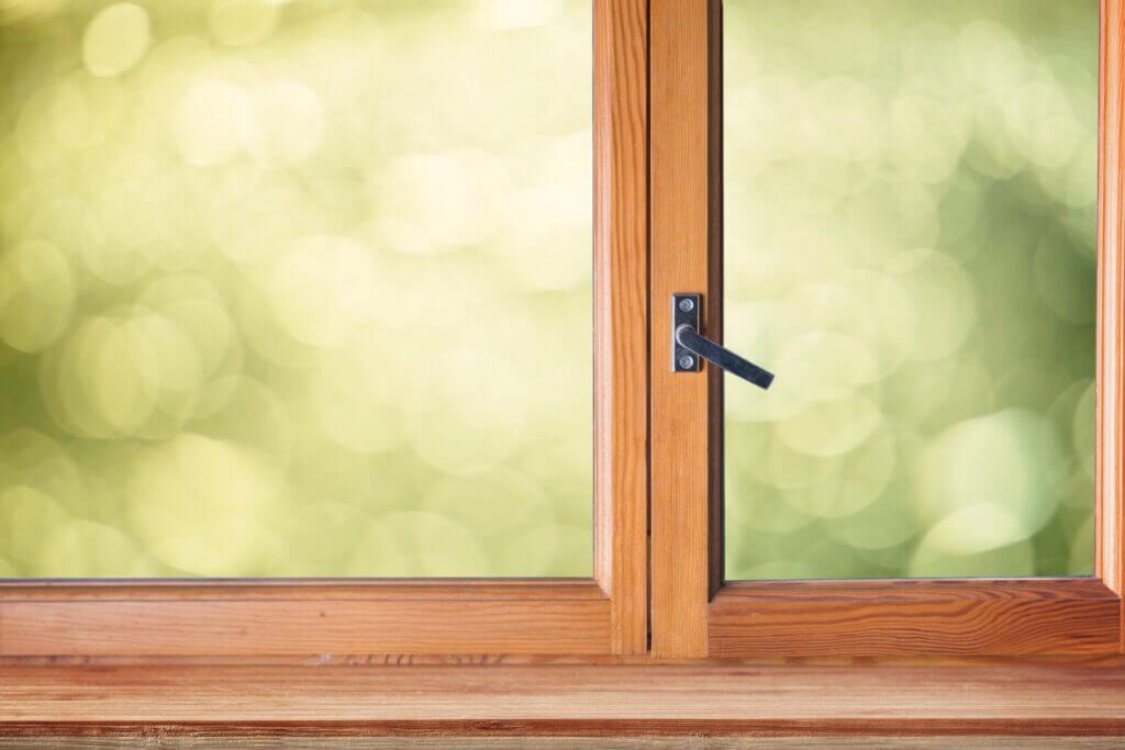 Polished wooden window frame with a metal handle, potentially prone to swelling from humidity.