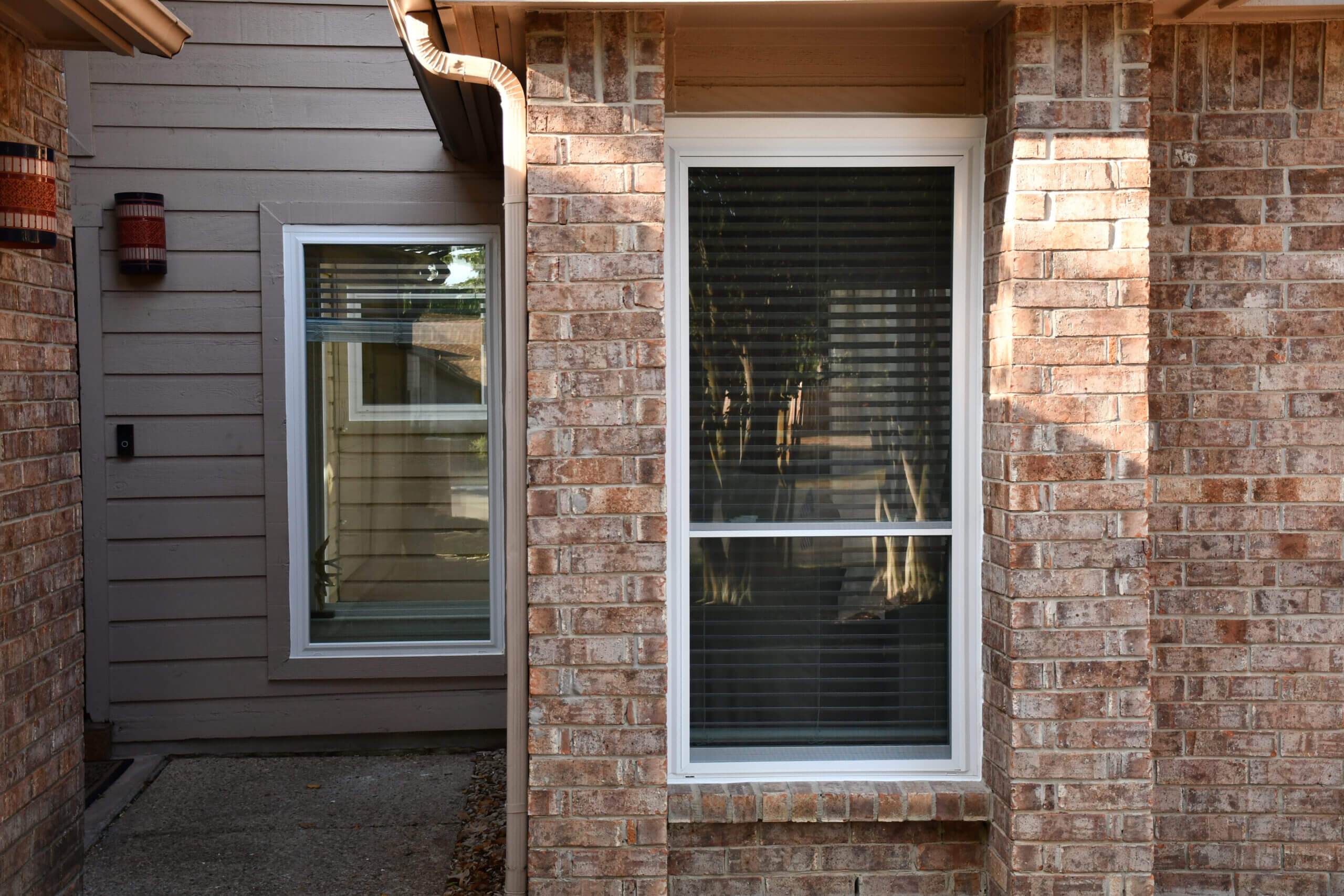 After photo of a professionally installed window by Texas Made Windows and More in a brick house with gray siding in San Antonio, Texas.