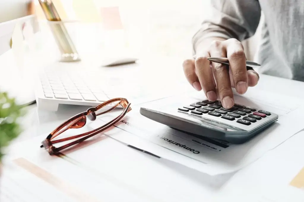 Person using a calculator to assess financial benefits of window replacement.