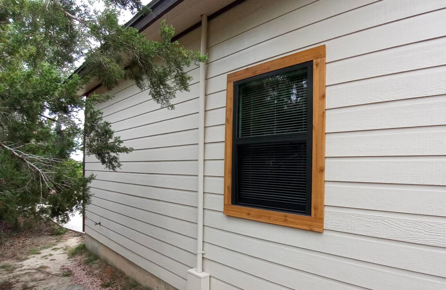 Side view of a home with a single energy-efficient window framed in natural wood.